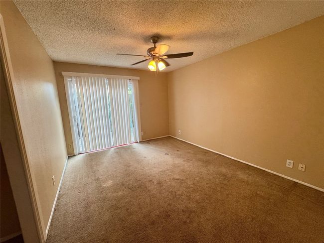 Empty room with ceiling fan, carpet, and a textured ceiling | Image 6