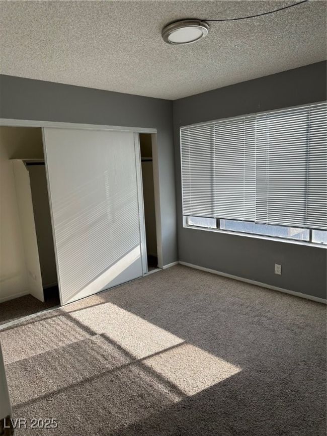 Unfurnished bedroom with carpet flooring, a closet, multiple windows, and a textured ceiling | Image 9