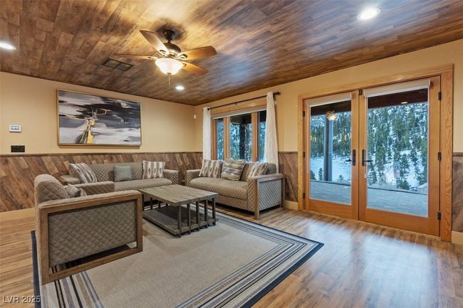 Living room with wooden ceiling, wood walls, wood finished floors, french doors, and wainscoting | Image 39