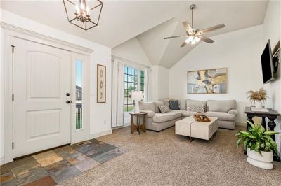 Carpeted living room featuring vaulted ceiling and ceiling fan with notable chandelier | Image 3