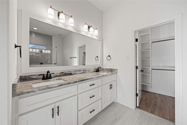 Bathroom featuring double vanity, tiled shower, a spacious closet, and baseboards | Image 20