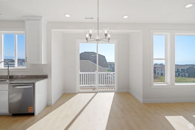 Unfurnished dining area featuring healthy amount of natural light, light wood finished floors, recessed lighting, and a chandelier | Image 11