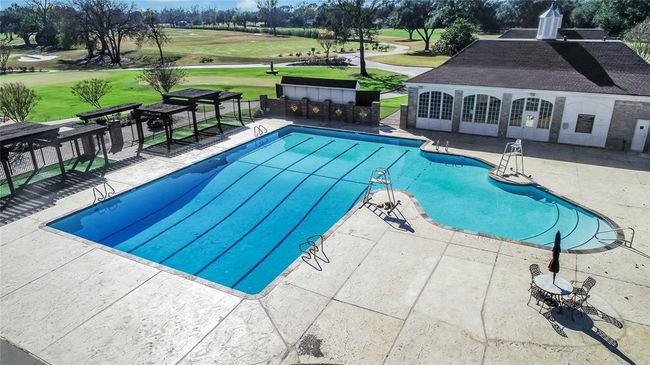 Enjoy resort-style relaxation at the Sugar Creek Country Club’s sparkling swimming pool. Perfect for unwinding or staying active, this spacious pool area features ample deck space, pergola-shaded seating, and scenic golf course views. Whether you're swimming laps, lounging in the sun, or gathering with friends, this inviting amenity enhances the luxury lifestyle of Sugar Creek living. | Image 46