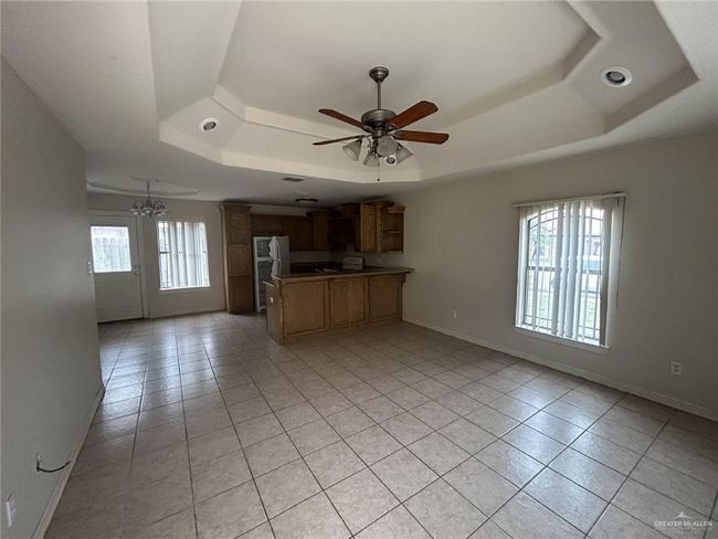 Kitchen with a tray ceiling, light tile patterned floors, freestanding refrigerator, a peninsula, and open floor plan | Image 13