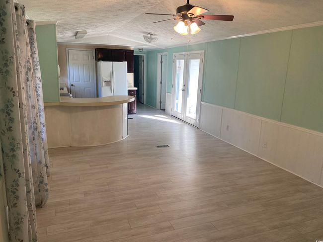 Unfurnished living room featuring vaulted ceiling, ceiling fan, light wood-type flooring, washer / clothes dryer, and a decorative wall | Image 9