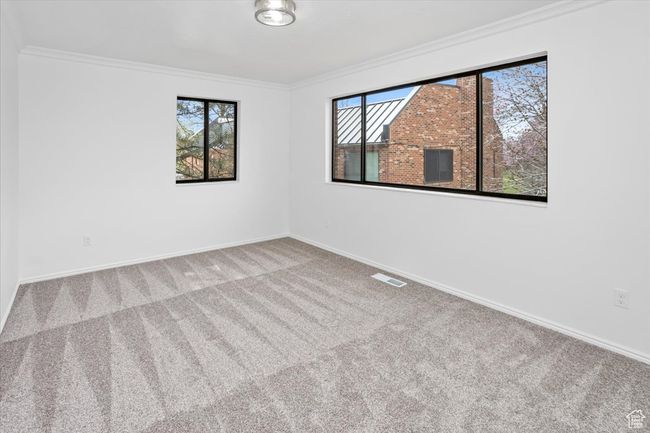 Unfurnished room featuring carpet flooring, plenty of natural light, ornamental molding, and visible vents | Image 25