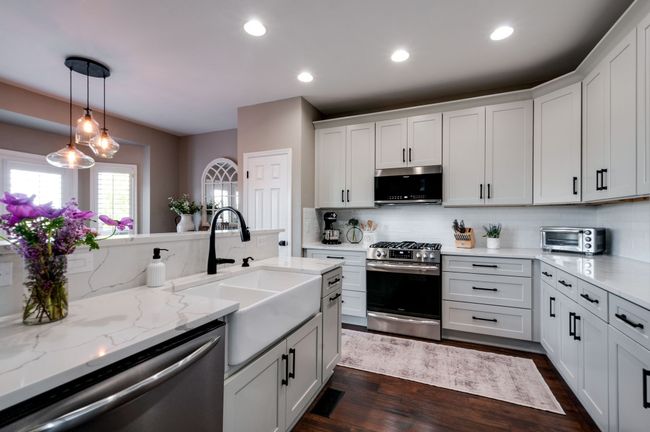 Fully renovated kitchen with new cabinets, quartz countertops, a farmhouse sink, a tiled backsplash and stainless steel appliances. | Image 19