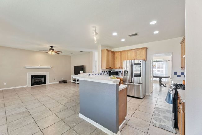 Kitchen with appliances with stainless steel finishes, light tile patterned floors, light countertops, a peninsula, and ceiling fan | Image 10