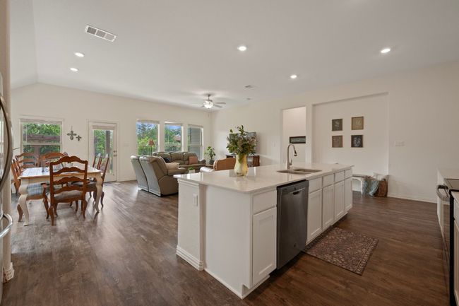 Kitchen with dishwasher, a sink, a ceiling fan, white cabinets, and dark wood finished floors | Image 5