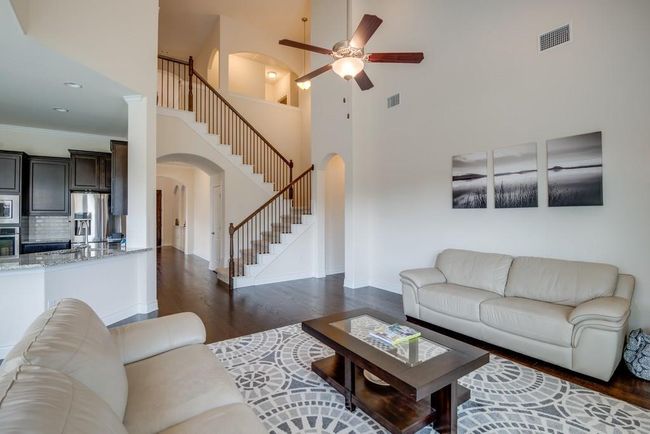 Living room featuring arched walkways, a ceiling fan, a towering ceiling, visible vents, and stairway | Image 14