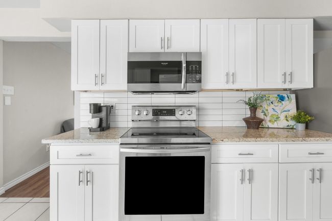 Kitchen with stainless steel appliances, baseboards, decorative backsplash, and light stone countertops | Image 22