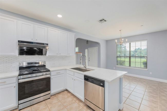 Kitchen with appliances with stainless steel finishes, arched walkways, light tile patterned floors, a chandelier, and recessed lighting | Image 13
