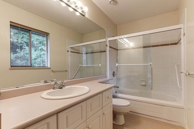 Full bathroom with vanity, bath / shower combo with glass door, tile patterned flooring, and toilet | Image 34