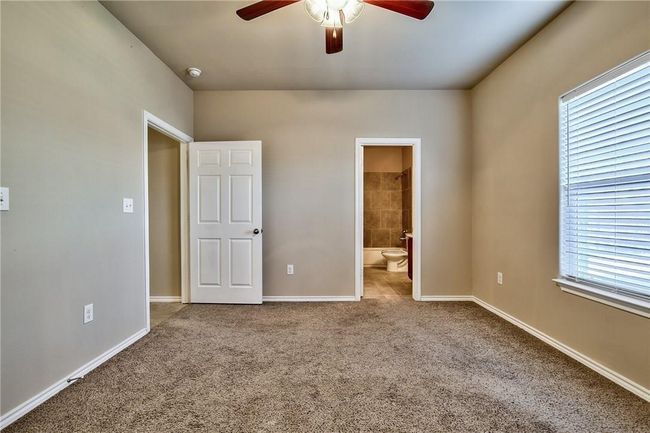 Unfurnished bedroom featuring carpet floors, connected bathroom, and ceiling fan | Image 10