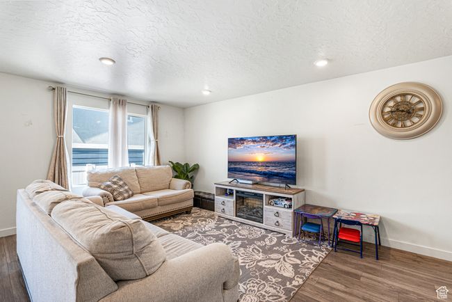 Living area with a textured ceiling, baseboards, wood finished floors, and recessed lighting | Image 7