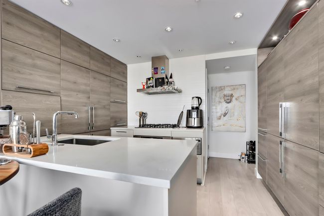 Kitchen with a sink, light countertops, light wood-style floors, modern cabinets, and backsplash | Image 8