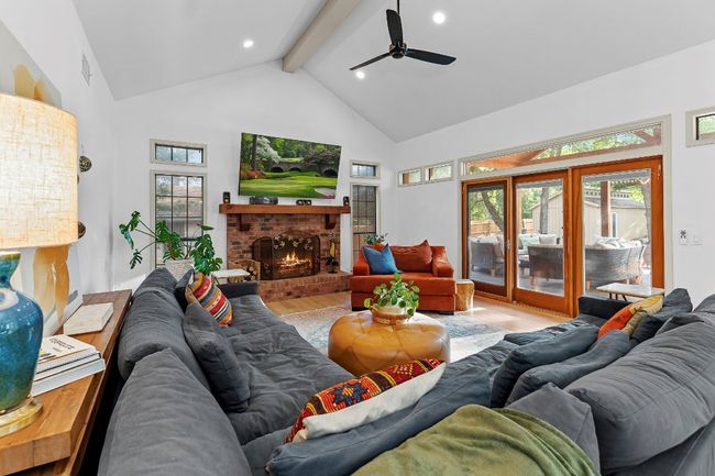 Living room with wood finished floors, beamed ceiling, high vaulted ceiling, ceiling fan, and a fireplace | Image 10