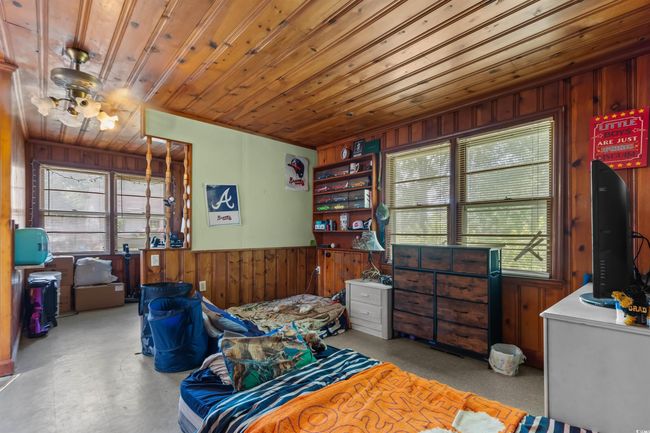 Sitting room with wood walls, wooden ceiling, concrete flooring, and wainscoting | Image 32