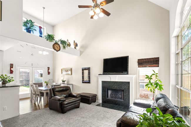 Living area with high vaulted ceiling, a ceiling fan, and a fireplace with flush hearth | Image 10