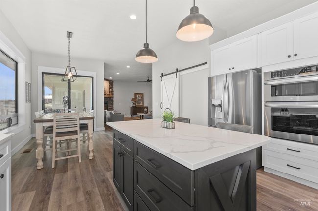Kitchen featuring stainless steel appliances, a barn door, white cabinetry, dark cabinets, and recessed lighting | Image 21
