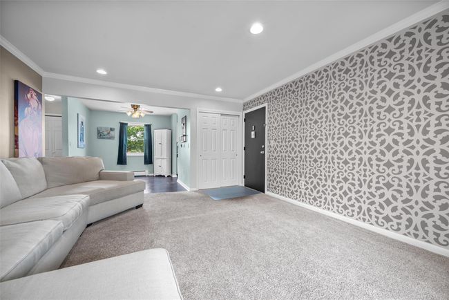 Carpeted living room with crown molding, recessed lighting, a baseboard radiator, and a ceiling fan | Image 10