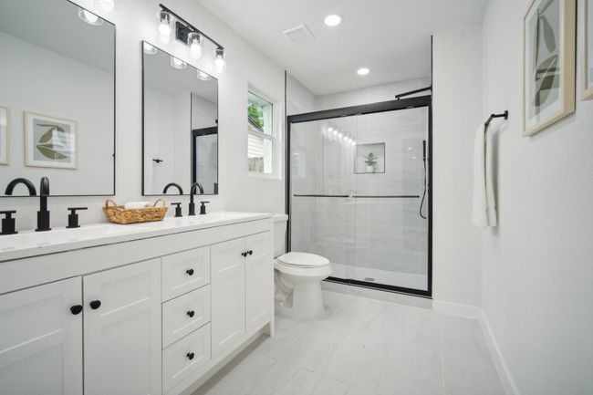 Bathroom featuring a sink, toilet, double vanity, and a shower stall | Image 15