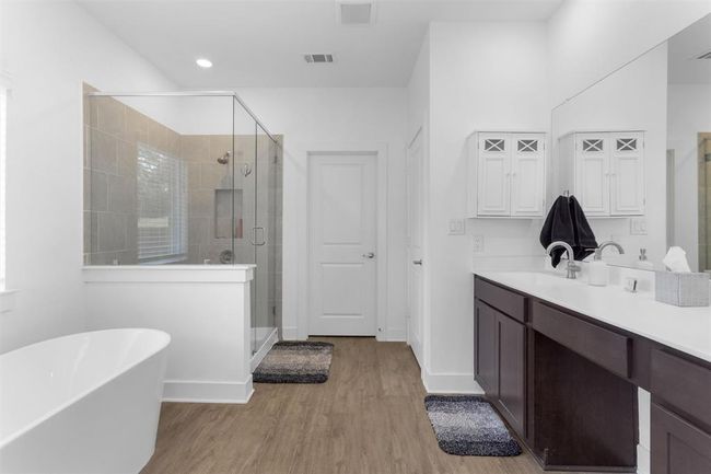 Spa-like luxury defines this bathroom, with double vanities, a soaking tub, a frameless glass shower, and finishes that exude elegance. | Image 22