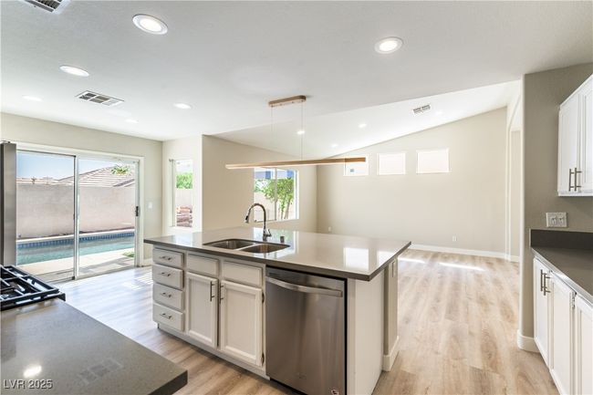 Kitchen with dishwasher, a sink, vaulted ceiling, light wood finished floors, and a kitchen island with sink | Image 9