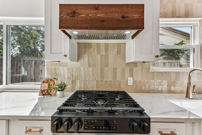 An entertainer’s dream kitchen with quartz countertops and sleek white cabinetry. | Image 11