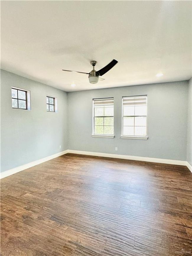 Empty room with ceiling fan, dark wood-type flooring, and recessed lighting | Image 14
