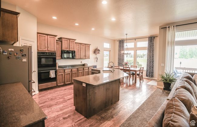 Kitchen featuring black appliances, open floor plan, light wood-style flooring, recessed lighting, and healthy amount of natural light | Image 7
