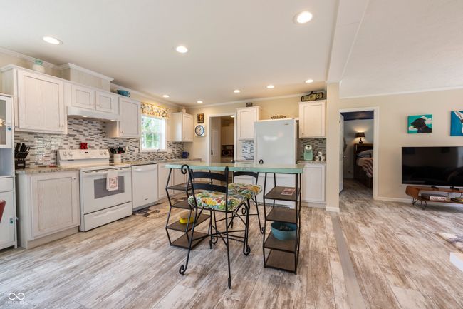 kitchen with white appliances, ornamental molding, backsplash, light wood finished floors, and recessed lighting | Image 16