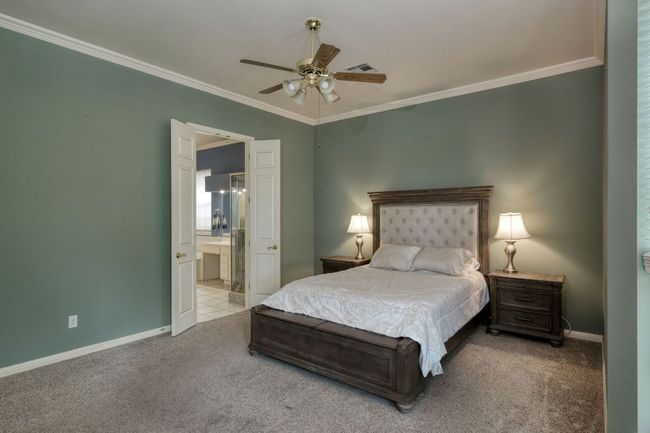 Carpeted bedroom with visible vents, ornamental molding, connected bathroom, baseboards, and ceiling fan | Image 16