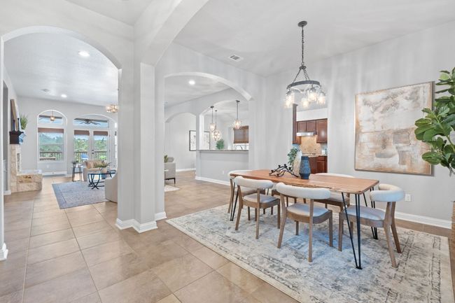 Dining space featuring a chandelier, arched walkways, recessed lighting, baseboards, and tile floors | Image 5