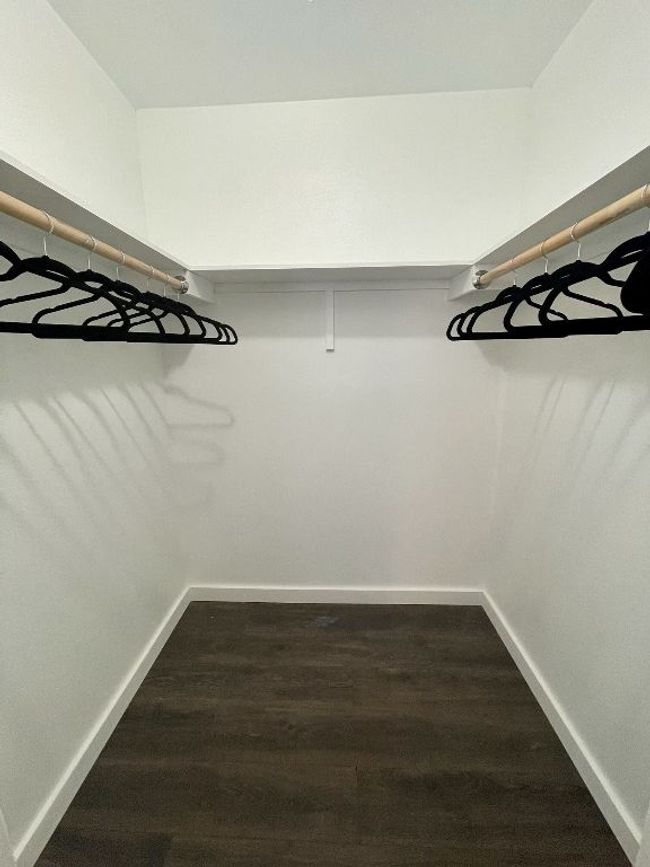 Walk in closet featuring dark wood-style flooring | Image 9