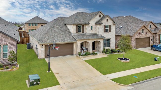 View of front of home featuring a shingled roof, brick siding, driveway, cooling unit, and a front lawn | Image 32