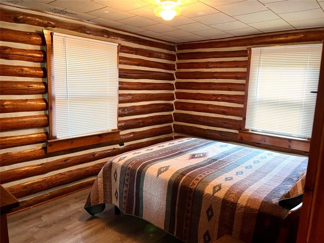 Bedroom with wood finished floors and log walls | Image 18