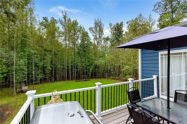 Wooden deck featuring a lawn, a view of trees, and outdoor dining area | Image 35