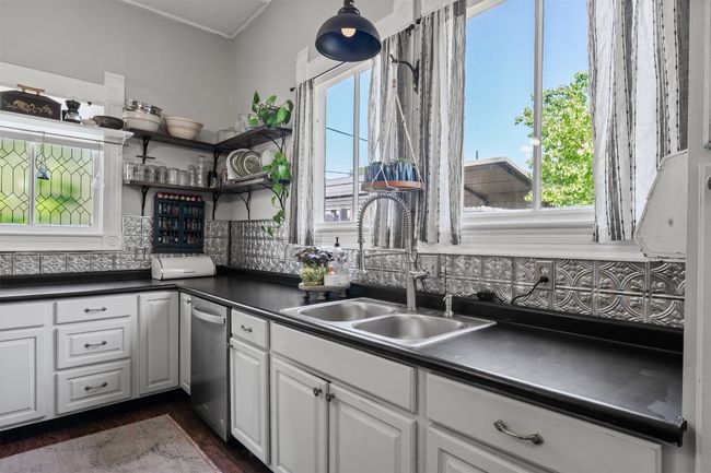 Kitchen with open shelves, dark countertops, white cabinetry, stainless steel dishwasher, and backsplash | Image 18