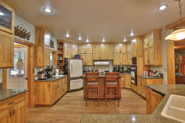 Kitchen featuring light wood-look floors, recessed lighting, freestanding refrigerator, a sink, and under cabinet range hood | Image 7