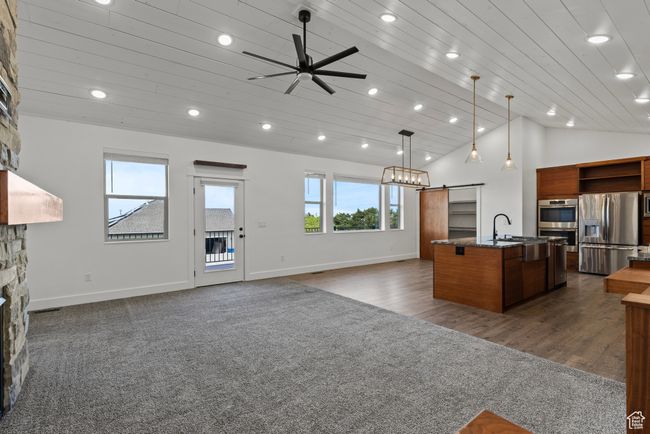 Kitchen featuring appliances with stainless steel finishes, a barn door, a kitchen island with sink, open shelves, and open floor plan | Image 4
