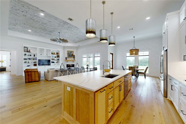Kitchen featuring a sink, appliances with stainless steel finishes, an island with sink, light wood-type flooring, and recessed lighting | Image 11