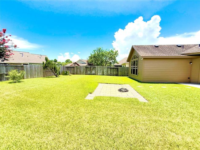 Spacious backyard with well-maintained lawn, stone pathway, and a wooden fence offering privacy. Perfect for outdoor activities and relaxation. | Image 26