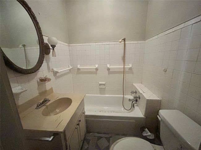 Full bathroom featuring tile walls, a tub, and vanity | Image 10