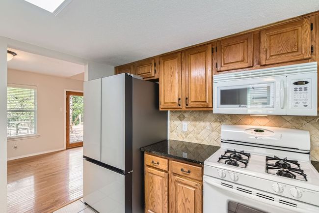 Kitchen featuring white appliances, backsplash, brown cabinets, and light wood-style floors | Image 10