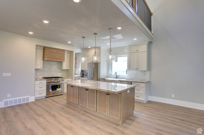 Kitchen with premium appliances, backsplash, recessed lighting, a center island, and light wood-style floors | Image 8