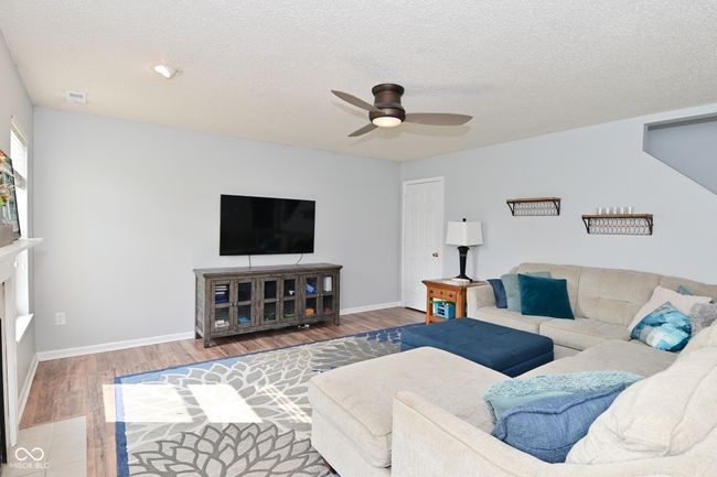 living area featuring wood finished floors, ceiling fan, a textured ceiling, and baseboards | Image 8