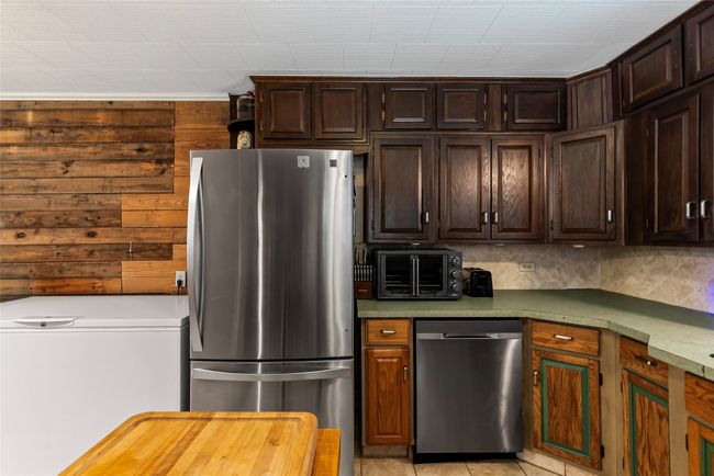Kitchen with appliances with stainless steel finishes, dark brown cabinetry, and tasteful backsplash | Image 6