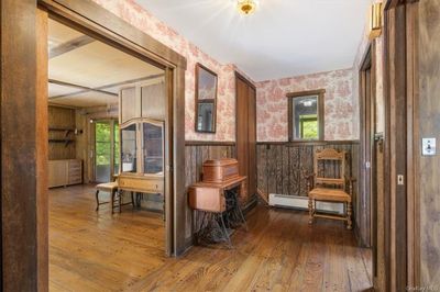 Hallway featuring hardwood / wood-style flooring, wood walls, and a baseboard radiator | Image 3