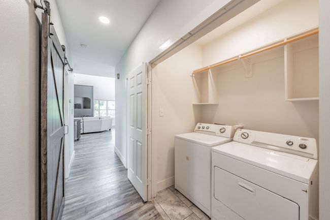 Washroom featuring washing machine and dryer, a barn door, light wood-style floors, and baseboards | Image 35